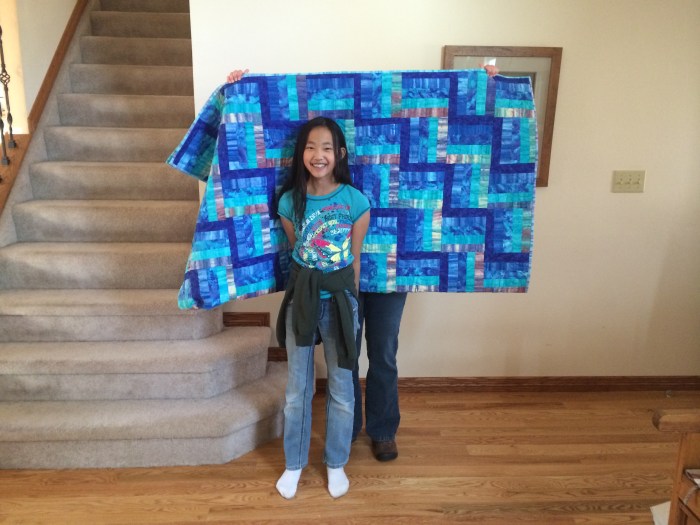 The quilt is folded over.  Barb's holding it behind Rachel.